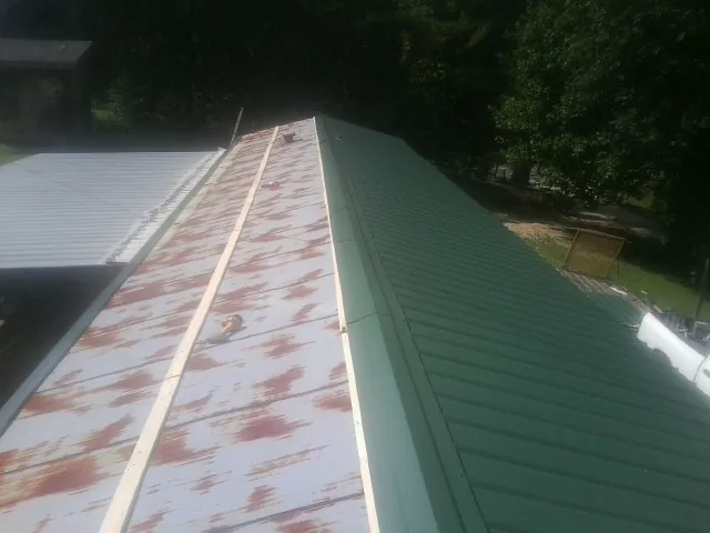 Old rusted panels beside newly installed green metal roofing — Wind Damage Roof Repair by Roofing Brothers in Oakwood