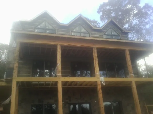 Dormers and porch framing on a large log home under construction — Roof Coating work by our crew in Oakwood