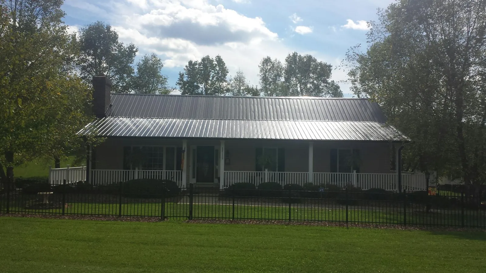 Gray metal roof on a brick ranch with a full width front porch — Gutter Guard Installation work by our crew in Oakwood
